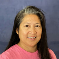 Jenny Ignacio is a Teacher of the Deaf at Listen and Talk's Blended Classroom Preschool Program for children who are deaf and hard of hearing. She has brown skin and dark hair and she is wearing a pink shirt.