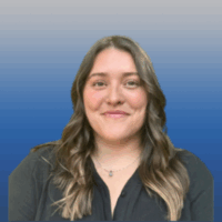 Photo of a woman with long brown hair and light skin smiling. She is wearing a black blouse and silver necklace.